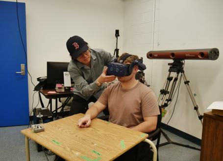 an image of michael wang fitting a vr headseat onto an undergrad research student
