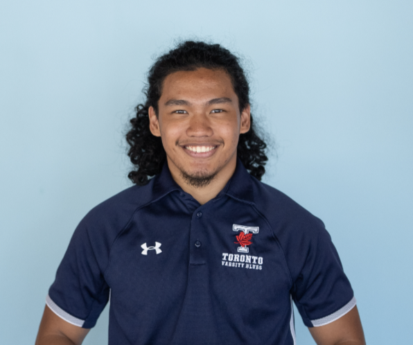 Headshot of Charles Viernes smiling and wearing a dark blue Varsity Blues t-shirt against a light blue background