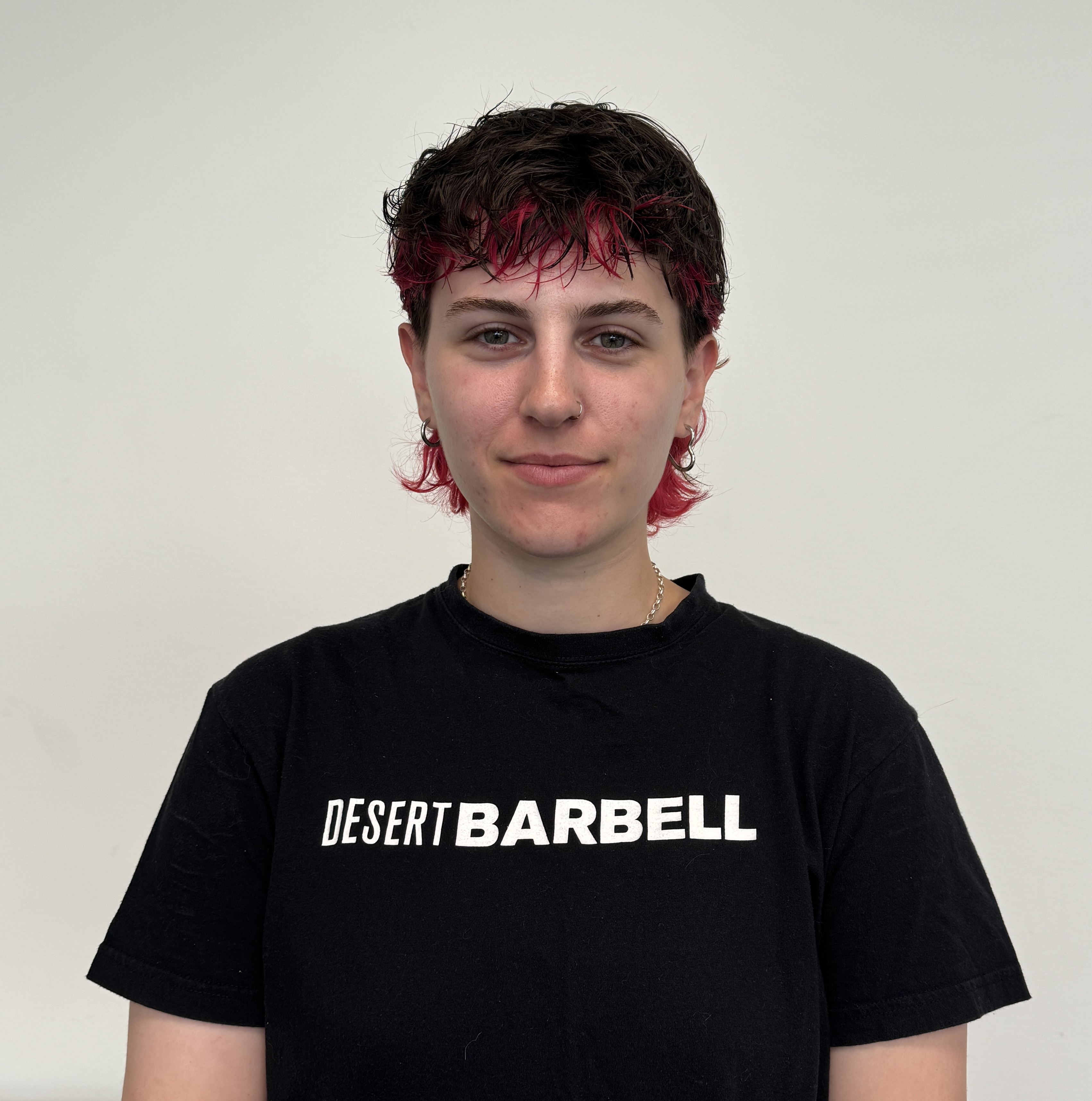 Headshot of Raiya Thomure in a black t-shirt against a cream-coloured wall