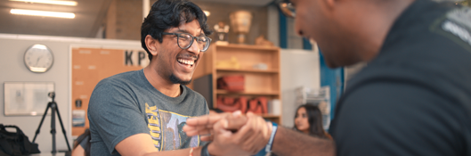 two male students smile and laugh with each other in the student lounge