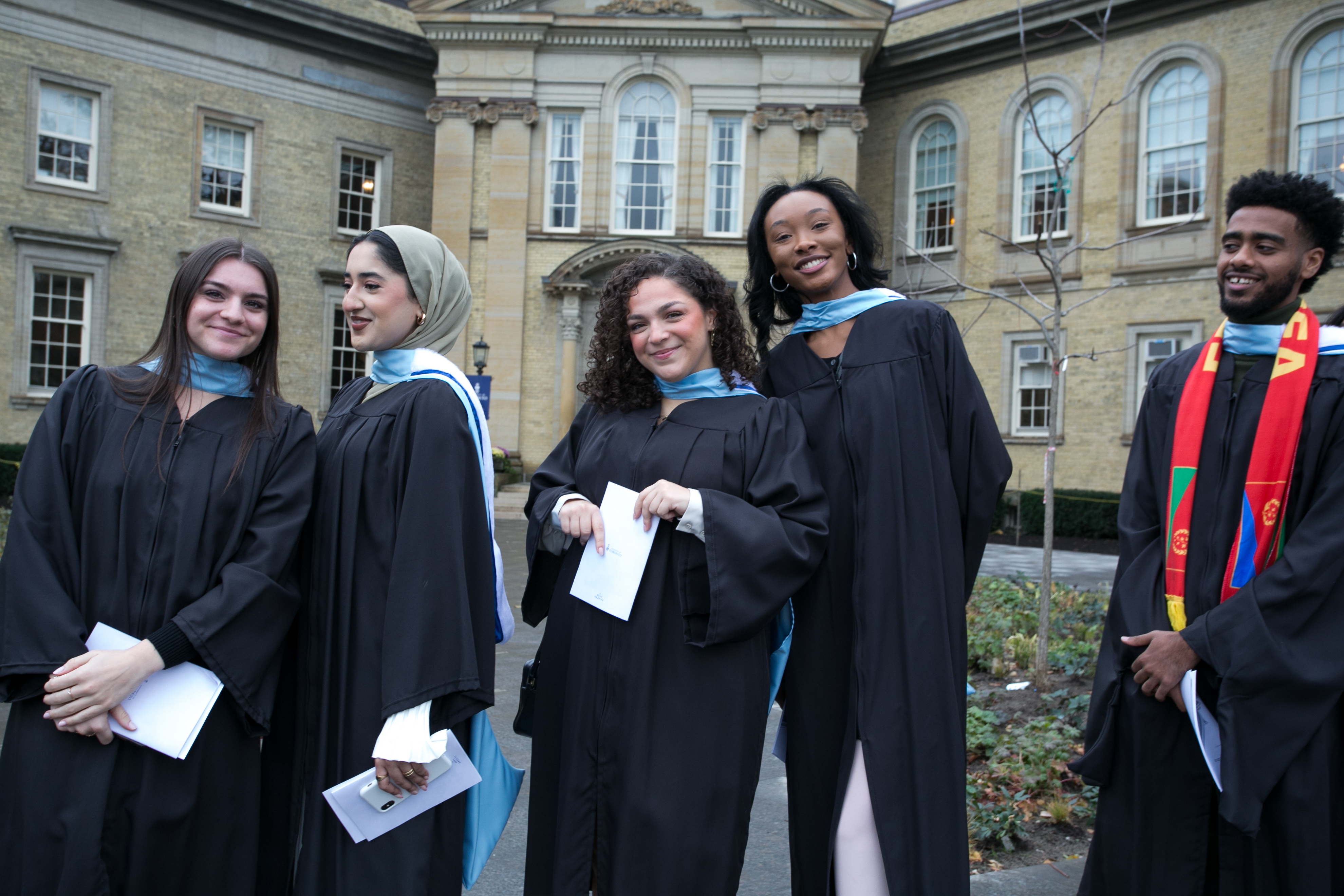 five students outside of simcoe hall in graduation gowns