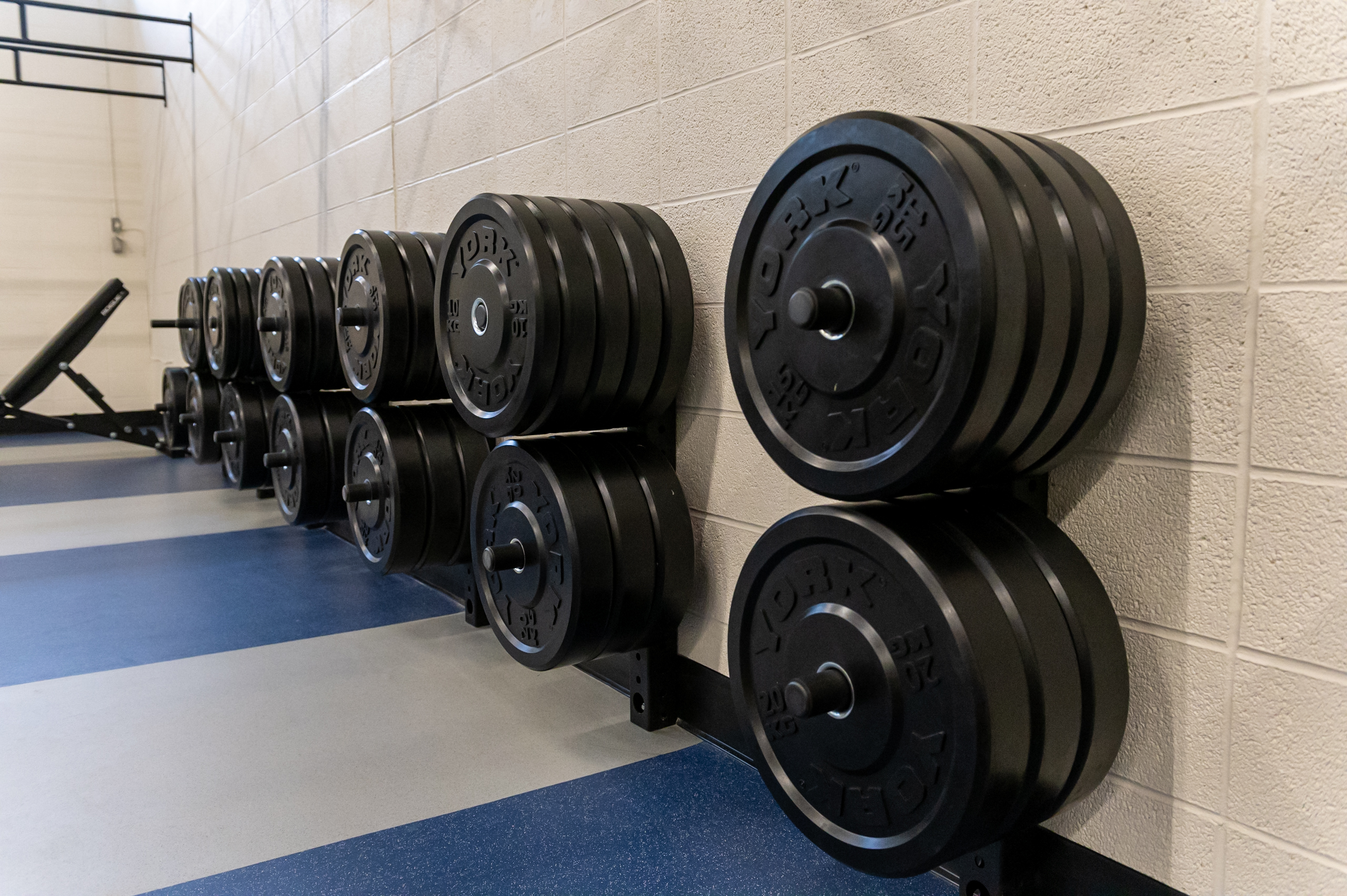 weight plates hanging on wall pegs in weightlifting zone room