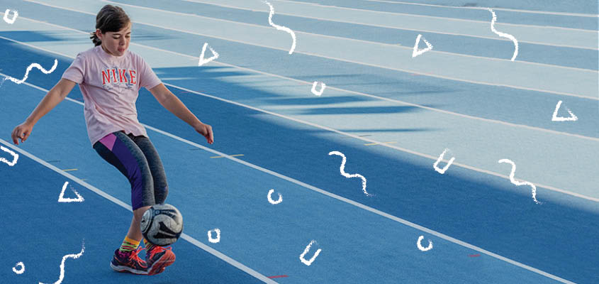 girl kicking a ball on a track