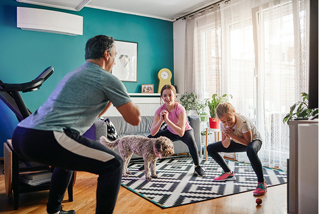 father exercising in living room with two daughters