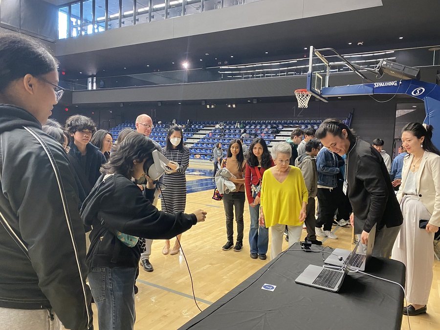 Michael Wang demonstrates his research on VR and AR to Vivenne Poy and other onlookers