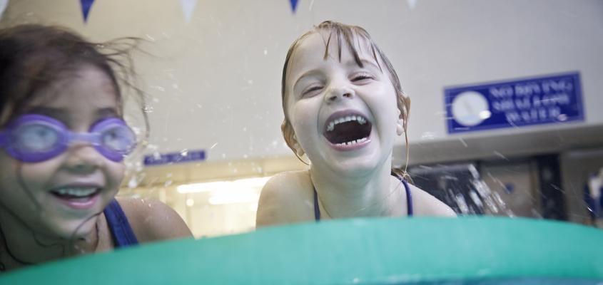 two young girls laughing and splashing in water