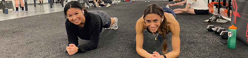 Two women planking while smiling