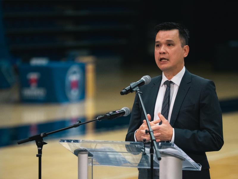 Daniel Do speaks at a podium in the Kimel Family Field House