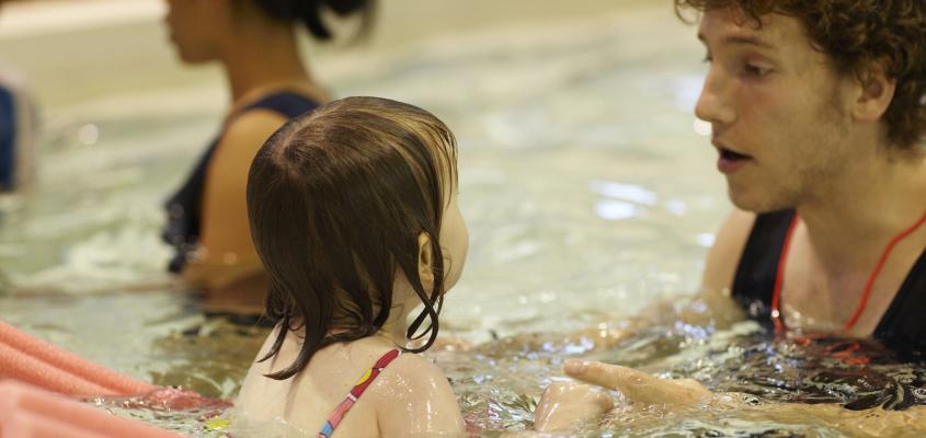 An instructor teaching a toddler to swim