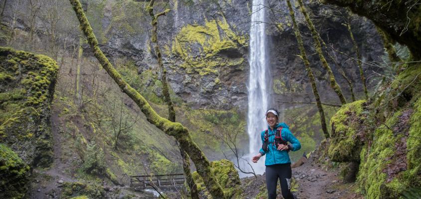 Professor Linda Trinh trail running past a waterfall 