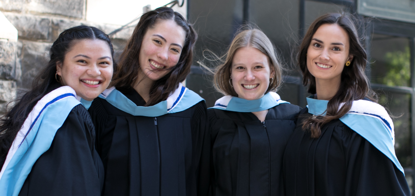 Four students pose for photo in graduation robes