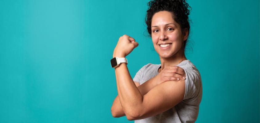 A study participant strikes a "Rosie the Riveter" pose in front of a blue backdrop