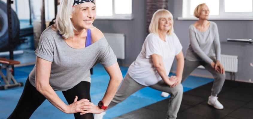 three older white women in exercise clothing lunging on gym mats