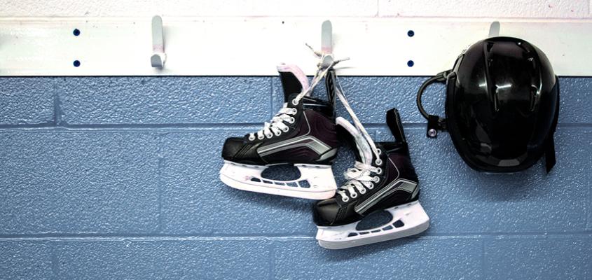 pair of ice skates and helmet hanging on hooks