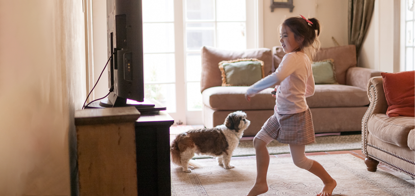 child exercising in front of tv with dog