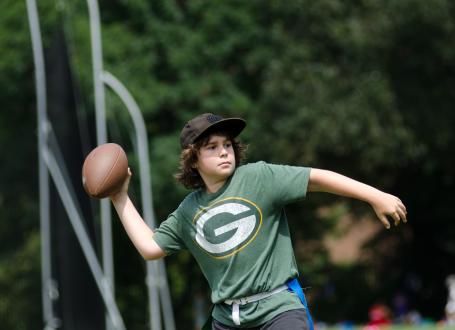 A young boy practices throwing a football