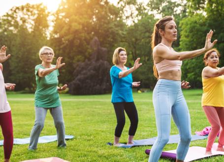 5 individuals doing a tai chi pose in a park