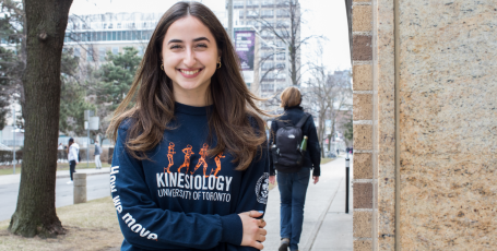 smiling female student wearing kinesiology-branded sweatshirt